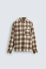 Camisa de corte relajado confeccionada en tejido de algodón con estampado de cuadros en tonos marrones y beige. Presenta cuello solapa, manga larga con puños abotonados, bolsillo plastrón en el pecho y cierre frontal con botones.