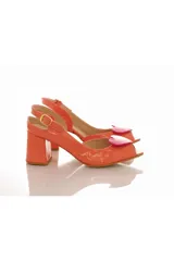 Sandalias de charol color naranja claro, con taco mediano forrado, tira ajustable al talón con hebilla dorada, puntera abierta y detalle de aplique en forma de corazón color fucsia.