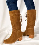 Bota de caña alta color suela, confeccionada en cuero napa, con diseño de caña caída y ajuste mediante cordones en la parte superior. Presenta un taco cuadrado foliado de 4,5 cm y suela de goma antideslizante.