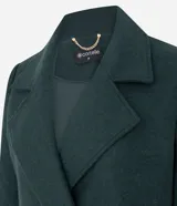 Abrigo largo de paño color verde oscuro, con solapas amplias tipo blazer, cierre frontal cruzado con botones y abertura trasera. Diseño estructurado y elegante.