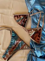 Conjunto de bikini confeccionado en terciopelo con efecto degradado en tonos azul, marrón y rosado. El corpiño es de estilo triangular con aros metálicos decorativos en el centro y breteles regulables. La bombacha es de corte clásico con laterales ajustables mediante tiras.