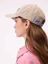 Gorra con visera curva de estilo clásico, confeccionada en algodón con efecto lavado. Presenta el logo de la marca Rusty bordado en el frente con letras en color rojo y borde blanco.