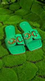 Sandalias negras con base cuadrada y tira ancha sobre el empeine, con aplique de cadena dorada.