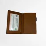 Billetera tarjetero compacta marca Liguria, modelo Portofino, color camel. Confeccionada en cuero genuino con estructura interna de aluminio, cuenta con tecnología RFID-blocking para protección contra robo digital y mecanismo de palanca para acceso rápido a las tarjetas.