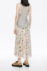 Falda midi plisada de silueta línea A, color crema, con estampado floral y rayas verticales en tonos pastel y tierra.