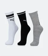 Kit de tres pares de medias deportivas Puma de caña larga. Un par es beige con dos rayas marrones y logo de Puma. Otro par es blanco liso. El tercer par es marrón oscuro con dos rayas blancas y logo de Puma. Todas están confeccionadas en algodón.