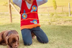 Chaleco de lana merino color rojo con flores bordadas a mano en azul y amarillo.