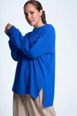 Sweater azul eléctrico de punto acanalado, con cuello redondo y mangas largas. Corte holgado con aberturas laterales.