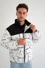 Campera puffer con diseño bicolor, presentando una parte superior en negro y el resto en blanco con estampado tipográfico de la marca. Posee cuello alto, cierre frontal completo y puños elásticos.