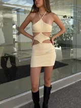 Minivestido color crema con escote halter asimétrico y aberturas en la cintura.