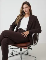 Blazer sastrero de corte entallado, color marrón chocolate, con cuello de solapa, hombreras estructuradas y cierre frontal con botón a tono. Cuenta con bolsillos laterales con solapa y forro interno.