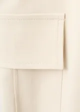 Pantalón cargo de tiro medio en color beige, con diseño recto, bolsillos de parche con solapa en los laterales y detalle de cinturón integrado en la cintura.
