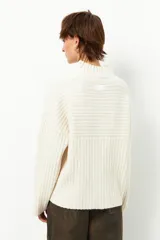 Polera gris de tejido tramado, cuello alto y mangas holgadas.