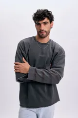 Sudadera gris oscuro de doble manga con efecto desgastado, cuello redondo y bordado frontal pequeño con texto.