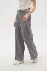 Pantalon de corte holgado y tiro alto, confeccionado en tejido de punto gris con costuras frontales verticales que simulan una tabla.