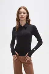 Remera de manga larga color negro, confeccionada en tejido técnico al cuerpo. Presenta cuello tipo polo con cierre frontal parcial y puños con abertura para el pulgar. Incluye un pequeño logo estampado en la manga.