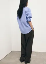 Camisa de corte recto con diseño de rayas verticales, cuello camisero clásico y cierre frontal con botones. Presenta mangas largas con puños abotonados.