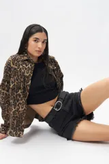 Short de jean negro con terminación desflecada y aberturas laterales. Presenta cuatro bolsillos.