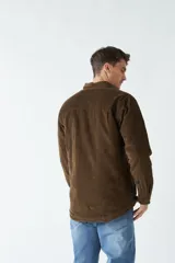 Chaqueta de pana color azul marino con interior capitoneado, cierre frontal con botones y bolsillos con solapa y botón en el pecho.