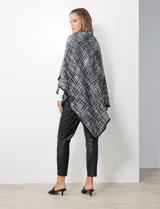 Capa de tejido tweed en blanco y negro, con cuello alto y cierre cruzado con botón de trenca.