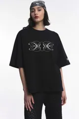 Remera negra de algodón suave, con corte boxy, cuello redondo y mangas cortas. Presenta un estampado frontal localizado en blanco con diseño simétrico y caligráfico.