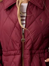 Campera acolchada de diseño matelassé con patrón de rombos, color bordó. Presenta cuello camisero, cierre frontal con cremallera metálica, cintura entallada con elástico y bolsillos laterales. Incluye un pequeño bordado distintivo en el pecho.