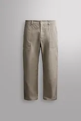 Pantalón de corte tapered fit color beige, confeccionado en tejido ligero de algodón con estructura rip stop. Cuenta con bolsillos de plastrón delanteros con acceso curvado, pinzas en las rodillas para mayor movilidad, y cierre frontal con cremallera y botón a presión.