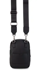 Bandolera pequeña de diseño compacto en color mostaza, confeccionada en material sintético con textura granulada. Presenta un bolsillo frontal con el logo de la marca impreso, cierre superior y correa ancha ajustable y desmontable.