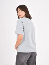 Remera de algodón color gris claro con efecto lavado, cuello redondo y detalle de pequeñas tachas metálicas dispersas en la parte superior delantera y mangas.