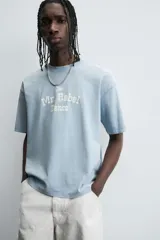 Camiseta de manga corta y cuello redondo, color celeste lavado, con estampado frontal en blanco que dice "The Mr. Rebel Dance".