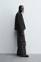 Cazadora de algodón color negro lavado, de corte relajado (relaxed fit), con cuello solapa a contraste, cierre frontal de cremallera, bolsillos canguro en la cadera y puños con botón a presión.