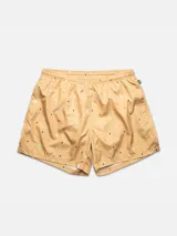 Short de baño color ocre con estampado de figuras abstractas en tonos pastel.