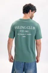 Remera manga corta de color verde con estampado tipográfico "Sailing Club Été 1983" en la espalda.