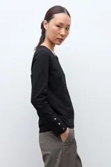 Remera de manga larga en color blanco, con cuello redondo y detalle de botones en los puños.