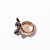 Anillo dorado con aplique de flor negra.
