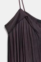 Vestido midi color morado oscuro, confeccionado en tejido satinado con efecto plisado o arrugado. Presenta escote en pico y tirantes finos ajustables. El calce es fluido y holgado.