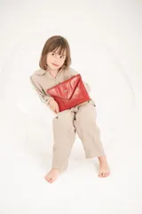 Cartera de fiesta tipo sobre color rojo charol con asa de cadena metálica plateada.