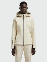 Chaqueta técnica Moncler modelo Zumeles, de color beige, con capucha ajustable, cierre frontal con cremallera termosellada y puños con detalle en contraste. Presenta un diseño entallado con bolsillos laterales y logo estampado en la manga.