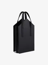 Bolso de hombro rígido color negro con asa superior en piel de becerro lisa mate con correa plana y dos compartimentos.