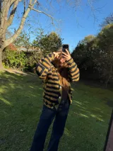 Saco corto de tejido de punto con diseño a rayas en tonos negro y amarillo, cuello destacado y cierre frontal con botones de nácar.