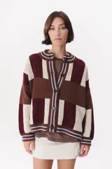 Cardigan de punto con diseño de bloques de color en tonos bordó, marrón y crema. Presenta cuello redondo, cierre frontal con botones, mangas largas con hombros caídos y terminaciones en rib con detalles de rayas celestes. Incluye logo bordado en el frente.