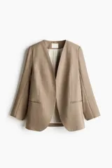 Blazer de sarga sin solapas color marrón, con hombreras, frente abierto, pinzas en la cintura, bolsillos delanteros ribeteados y forro interior.