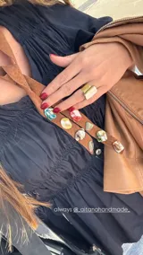 Corbatín de cuero marrón con piedras de colores incrustadas.