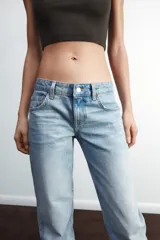 Jeans de mezclilla azul oscuro con efecto lavado, tiro bajo y pierna ancha extra larga. Modelo de cinco bolsillos con cierre frontal de cremallera y botón metálico.