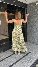 Vestido largo estampado con escote en V profundo y tirantes anchos. El diseño presenta un frunce o nudo en el centro del busto y tajos laterales en la falda.