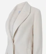 Saco femenino de corte alargado, color crema, con solapa amplia, cierre frontal de dos botones y bolsillos laterales embutidos.
