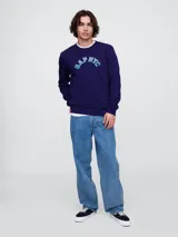 Buzo deportivo Gap color crudo, de corte recto, con cuello redondo y logo Gap NYC estampado en verde.