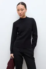 Sweater de punto color crudo con cuello alto tipo media polera, manga larga y diseño con textura de líneas horizontales. Presenta un borde inferior con terminación ondulada.