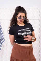 Remera baby tee negra de algodón, con cuello redondo y mangas cortas. Cuenta con un estampado frontal en color blanco de estilo vintage con la inscripción "Strive to be better" y un diseño gráfico de un tren.