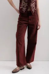 Pantalón de jean color borgoña, corte baggy, tiro medio, con cuatro bolsillos y pinzas en las rodillas.